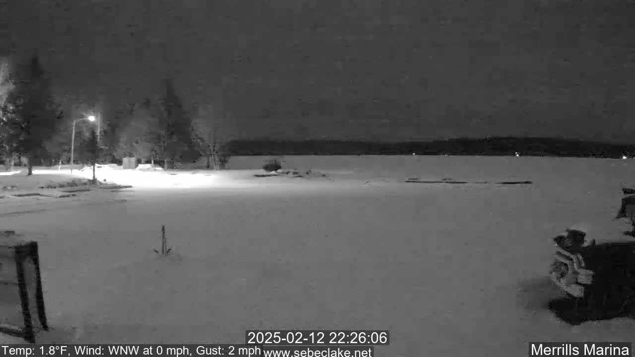 A snow-covered parking lot and frozen lake are visible at night under a dark sky.