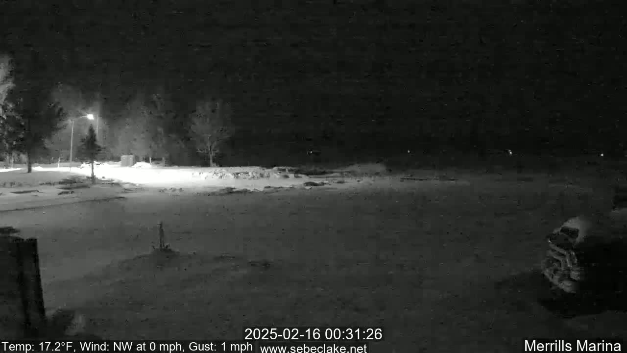 A snow-covered parking lot is dimly lit at night under a dark sky.