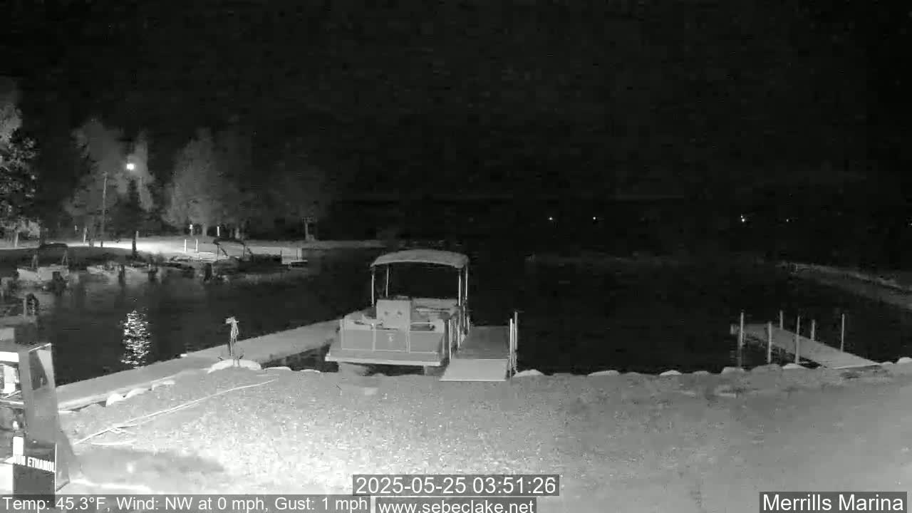 A pontoon boat is docked at a marina at night under a calm, dark sky.