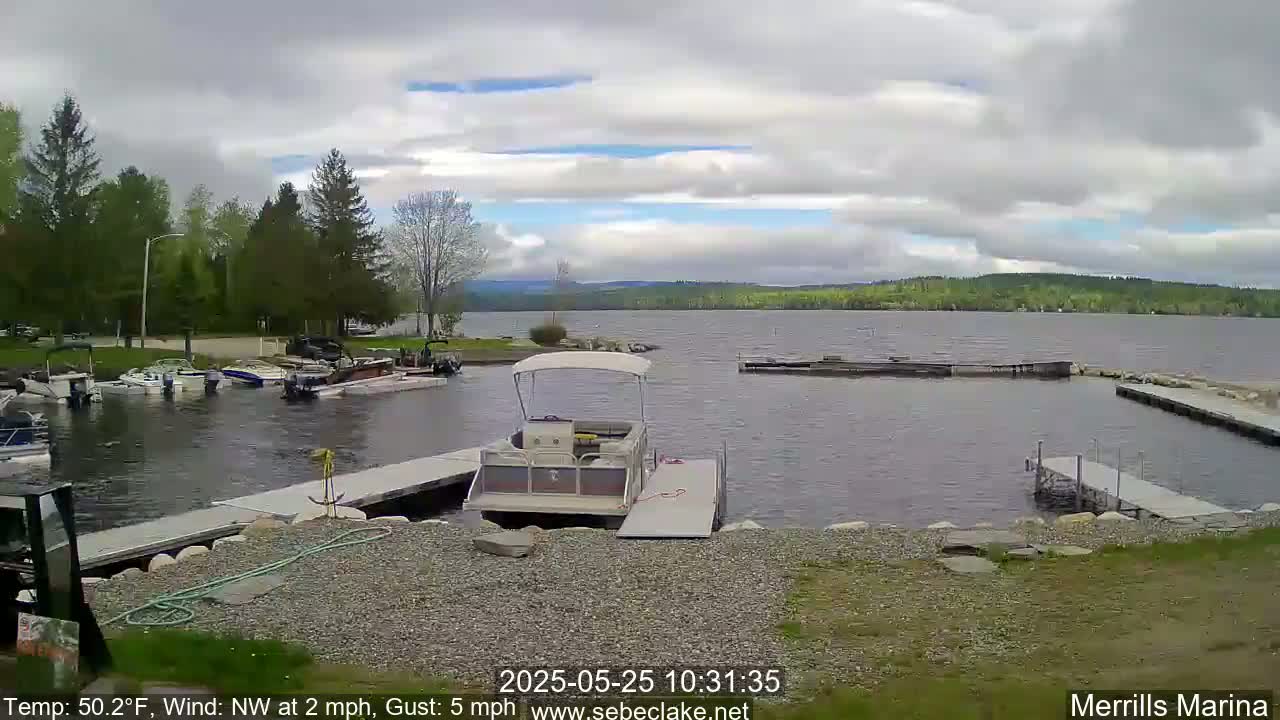 A pontoon boat sits at a marina on a partly cloudy day with a northwest wind.