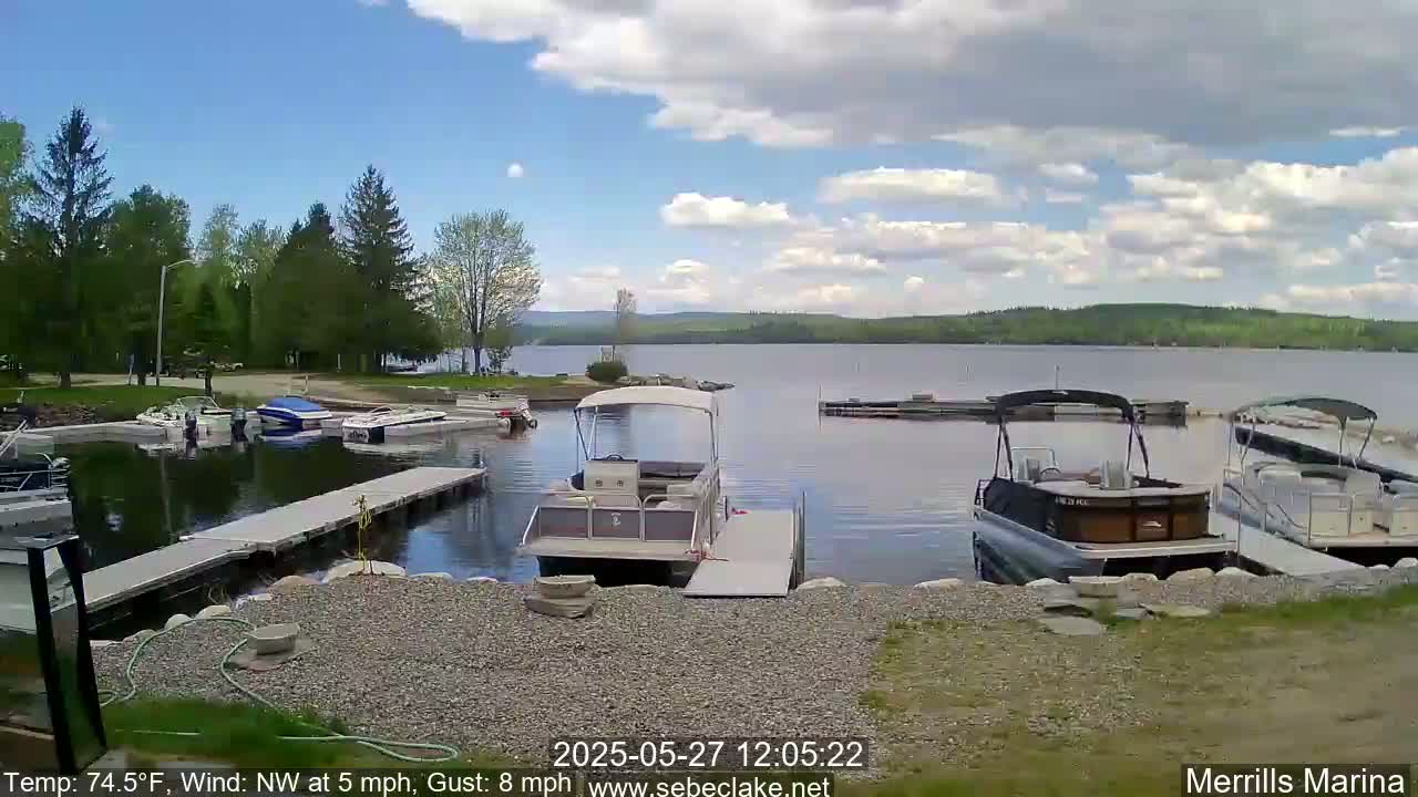 Several boats are docked at a marina on a partly cloudy day with a northwest wind.