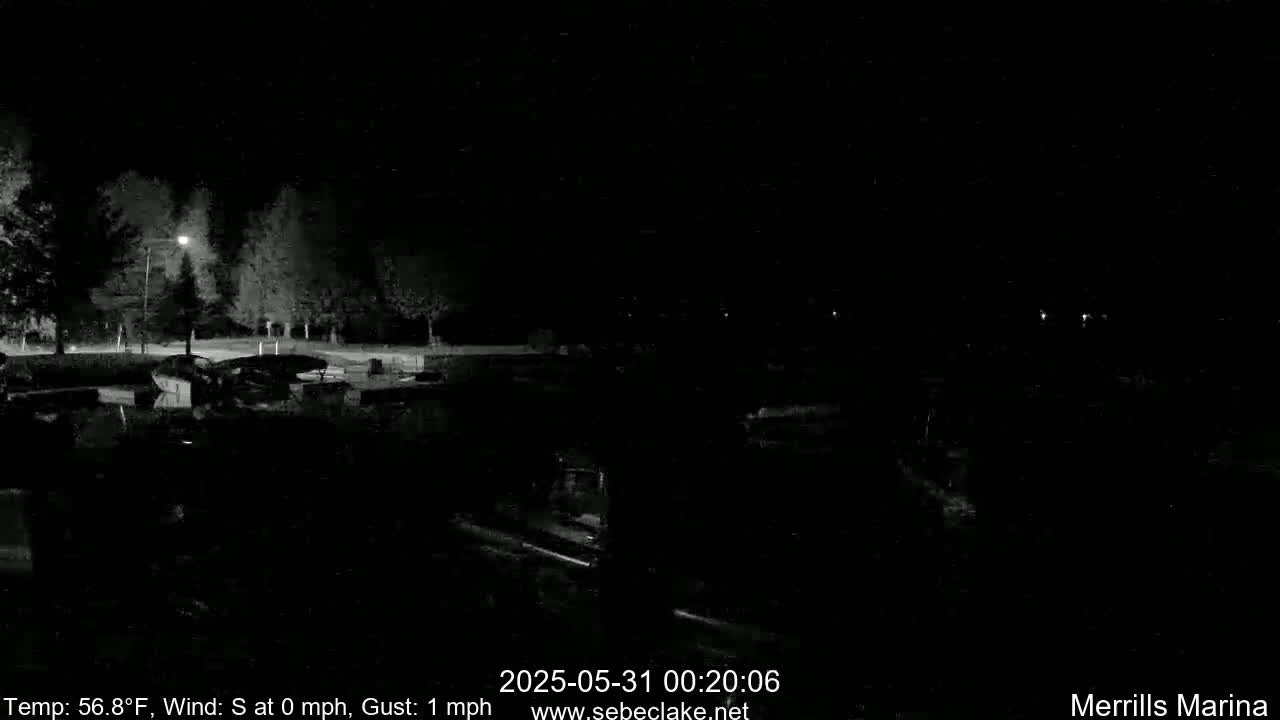 A nighttime, low-light view of a marina with boats and trees, under calm conditions with a temperature of 56.8°F.