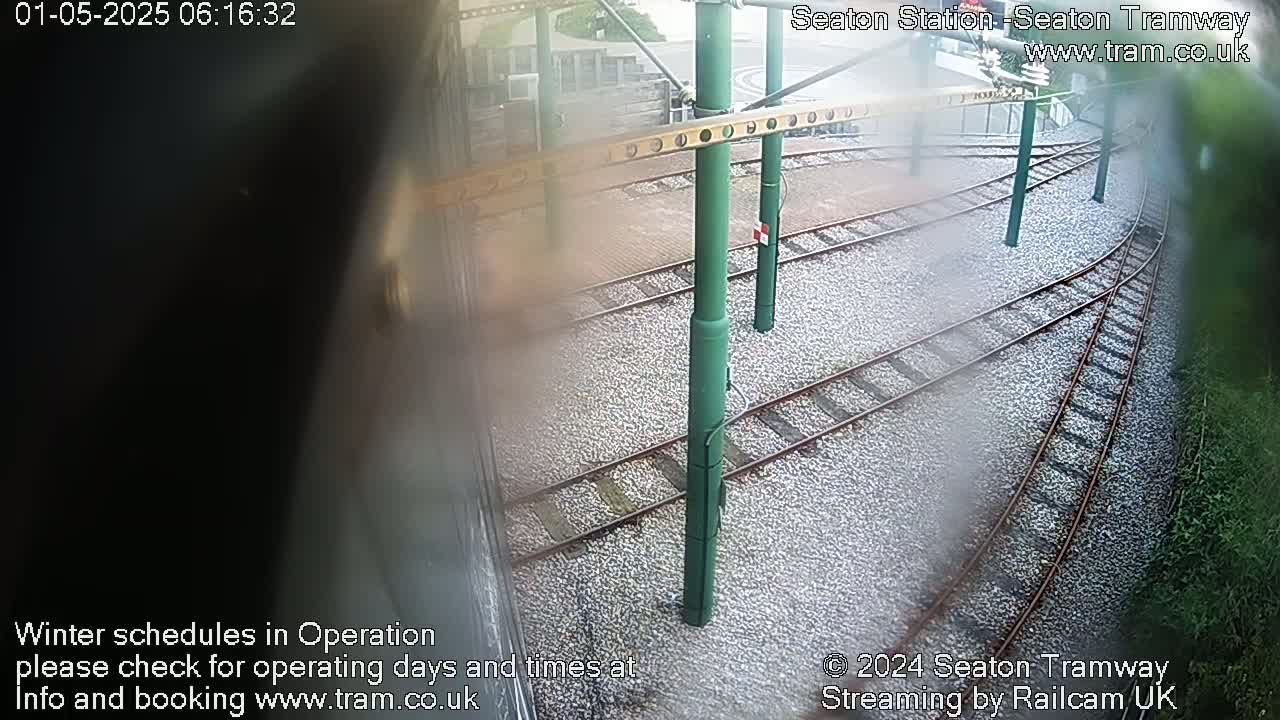 A high-angle view shows a tram station's tracks and infrastructure on a slightly overcast day.