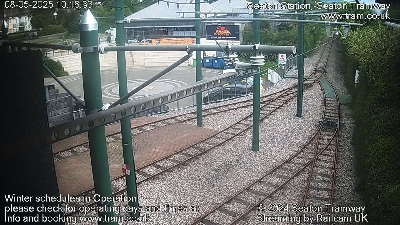 Tram tracks curve around a paved area near a building, under an overcast sky.