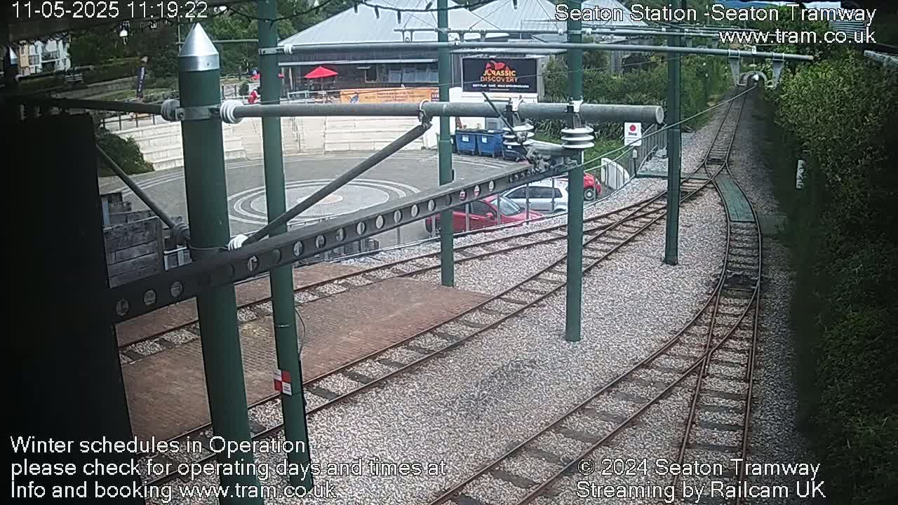 A high-angle view of a tram station with two cars parked near the tracks, under an overcast sky.