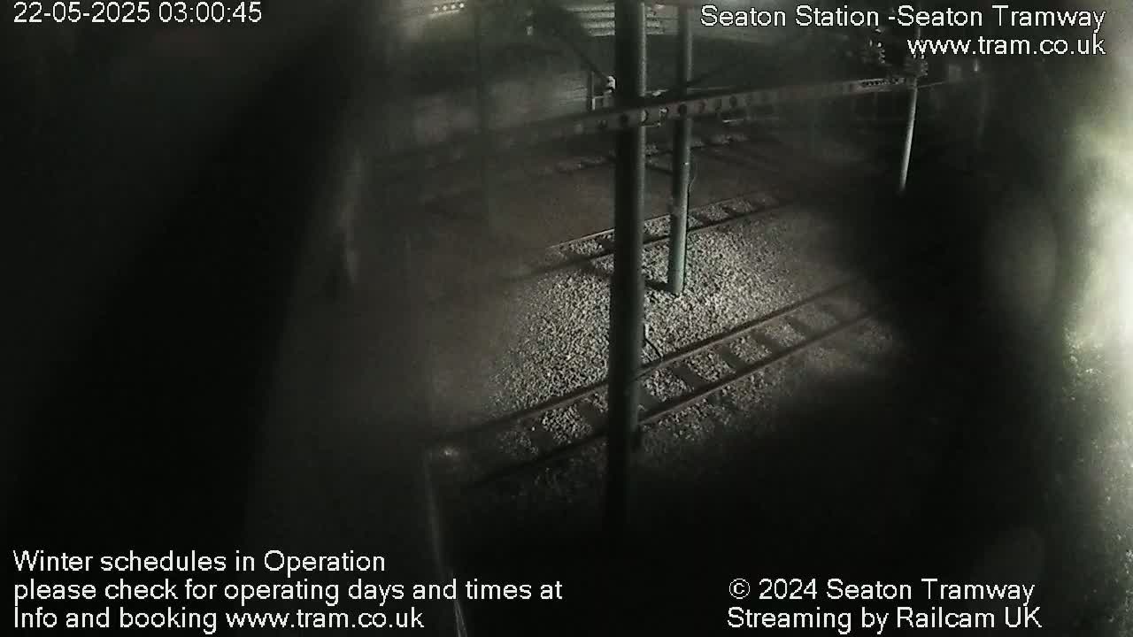 A dark, nighttime view of train tracks and supporting infrastructure.