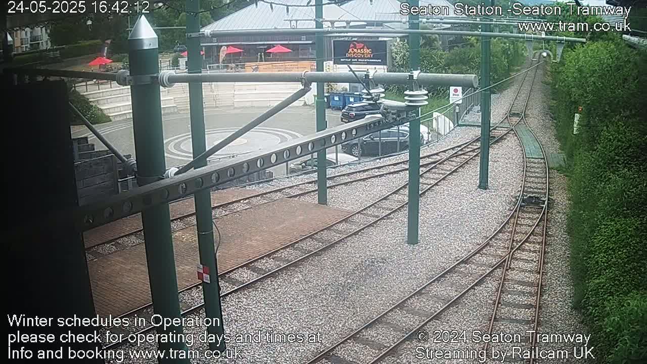 Tram tracks curve around a station platform in front of a building, under overcast skies.