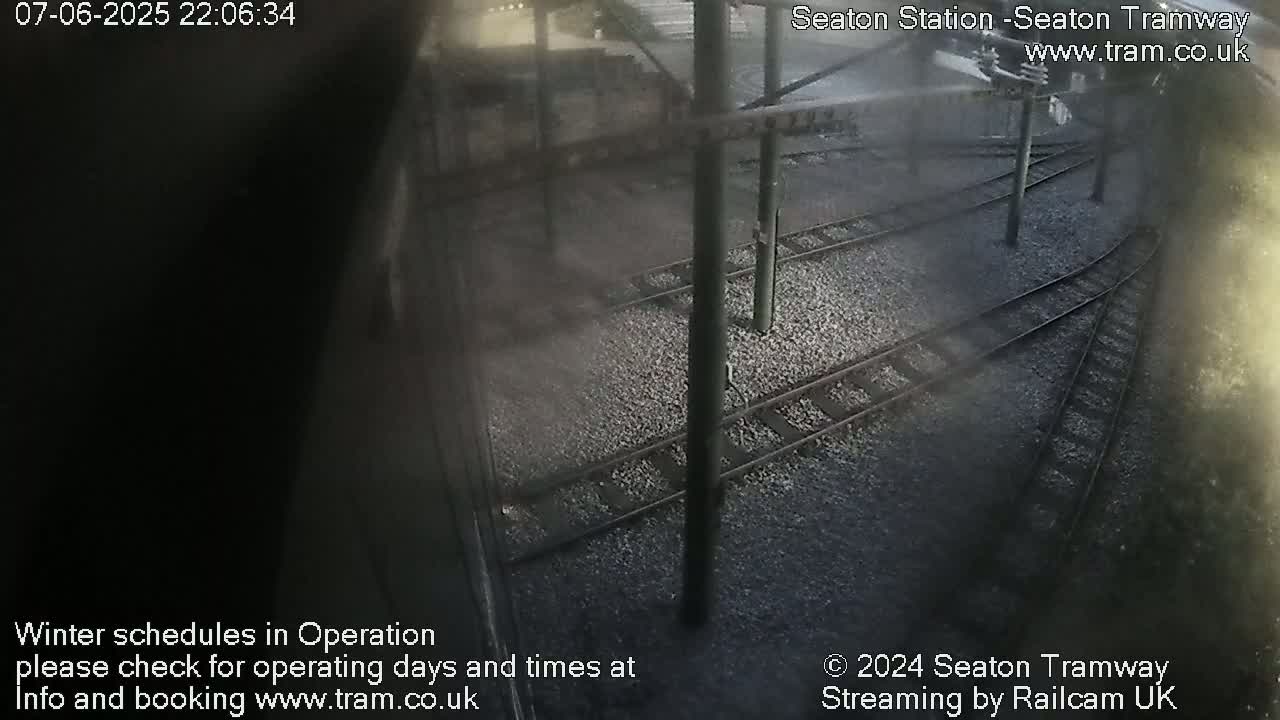 An overhead view of train tracks at night, showing two sets of tracks converging.