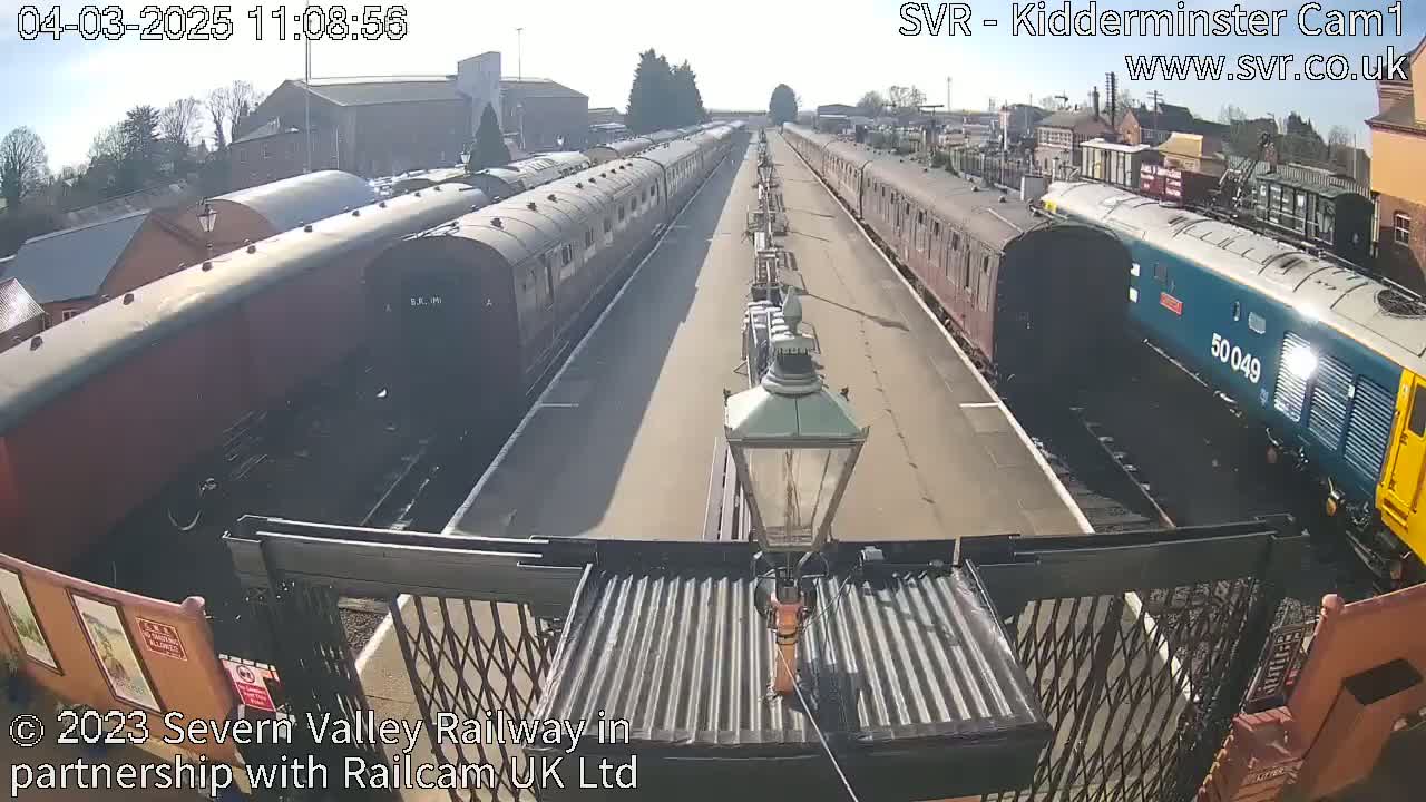 Two long lines of railway cars are parked on sunny railway tracks.