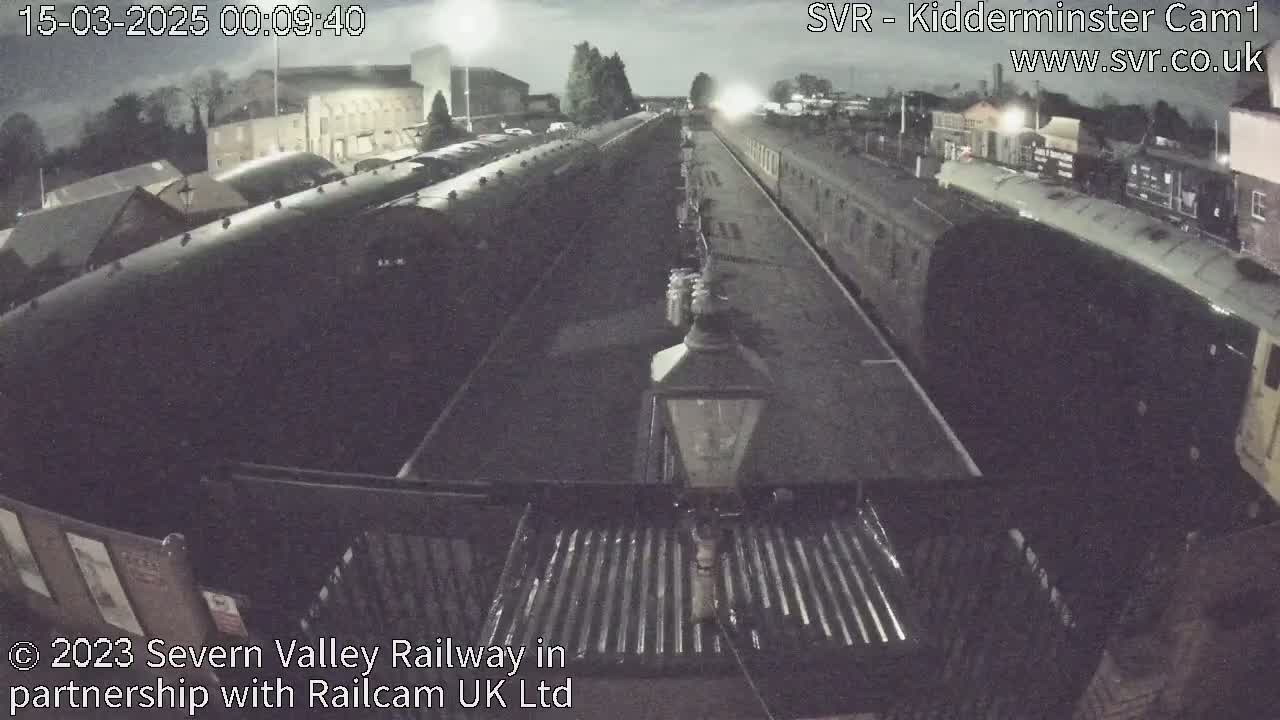 A nighttime, overhead view of a railway station with several trains parked on tracks.