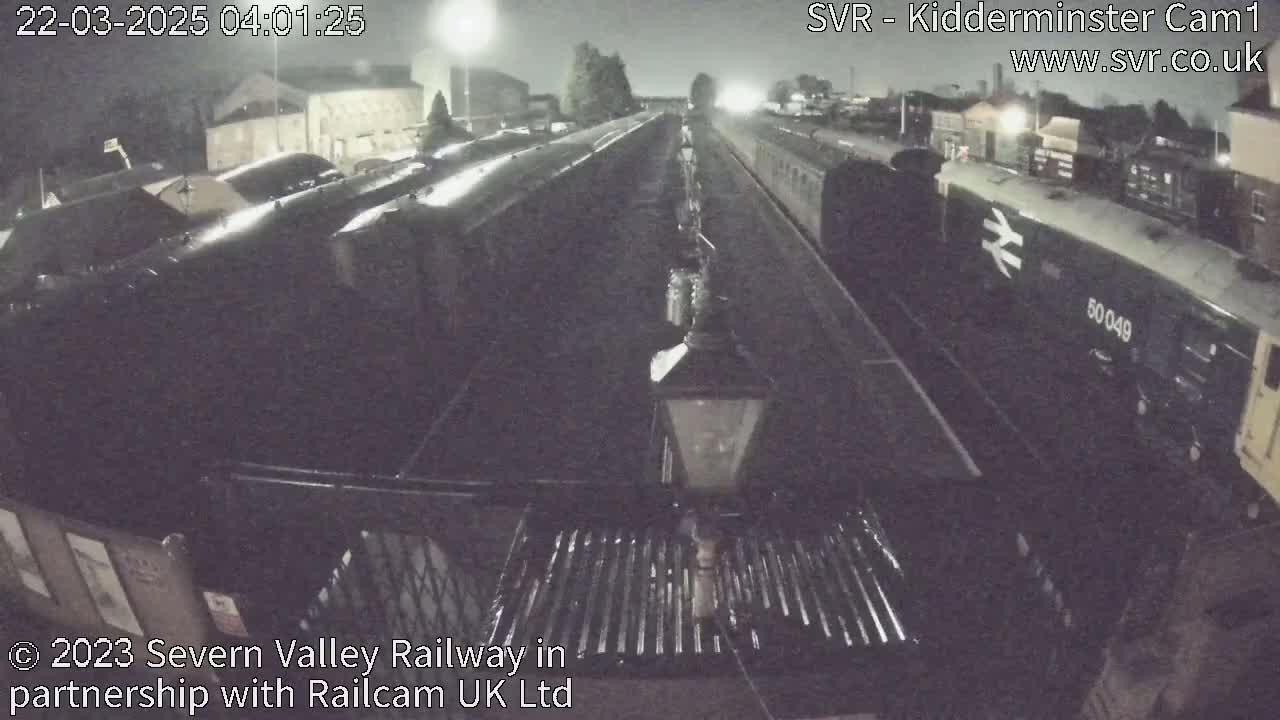 At night, a train sits in a station yard under dim lighting.
