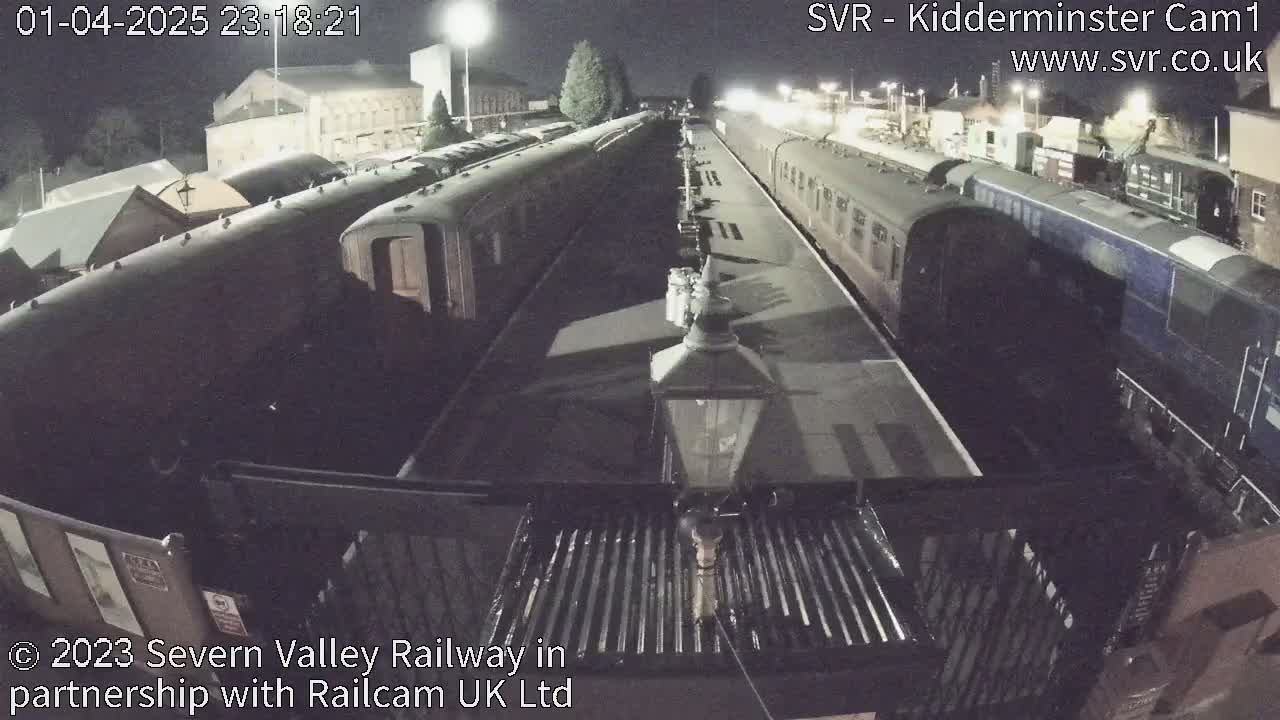 Several passenger train cars are parked at a station at night.