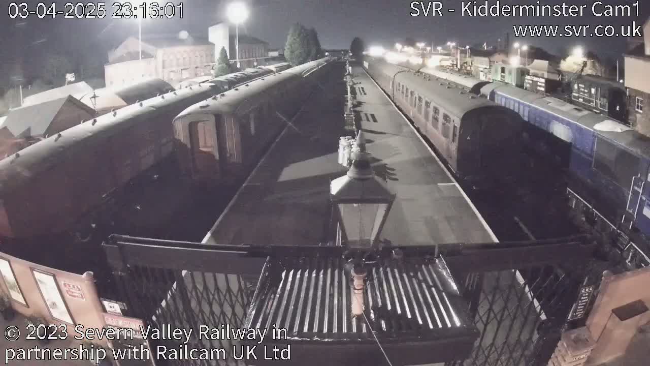 At night, several passenger train cars are parked on a platform at a train station.