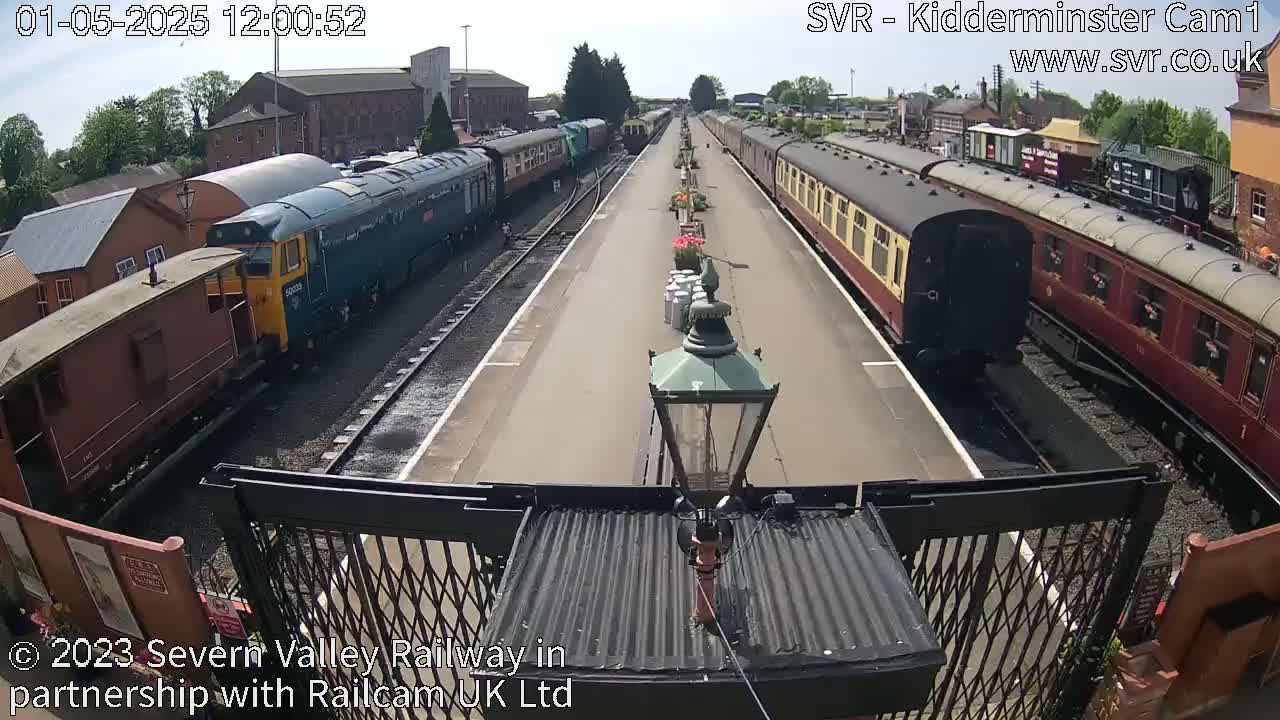Several passenger and freight trains are parked at a railway station on a sunny day.