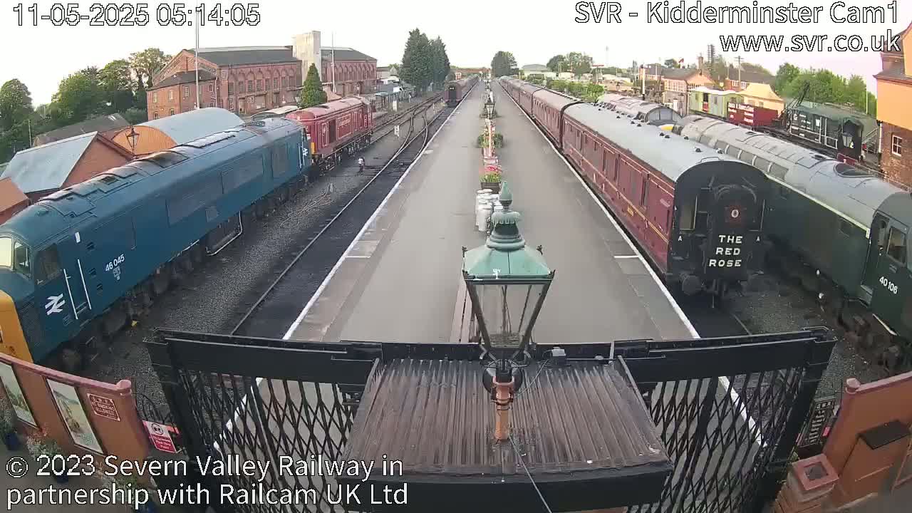 A high-angle view shows several trains on a railway track under an overcast sky.
