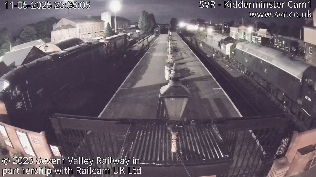 At night, several locomotives are parked at a train station platform.