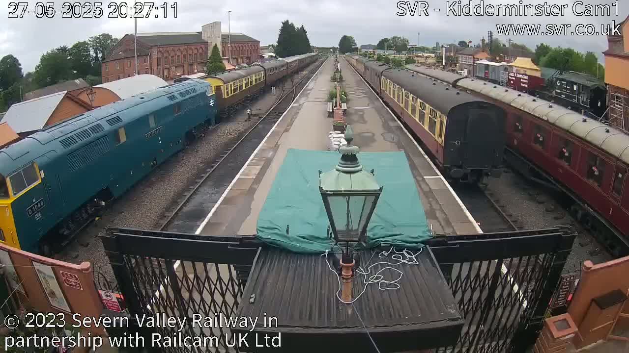 A train station with multiple passenger trains on tracks under an overcast sky.