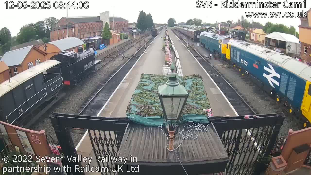 A railway station with several trains on the tracks under an overcast sky.