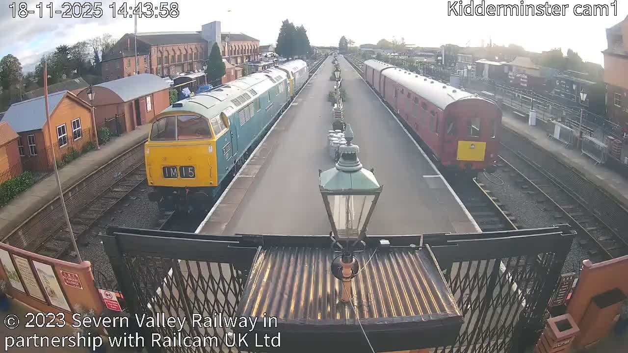 A nighttime, overhead view of a train station with several dark-colored train cars parked on the tracks.