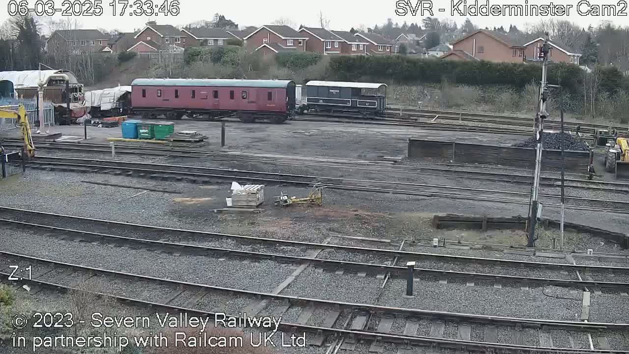 Several railway cars sit on a network of train tracks in a railway yard on an overcast day.