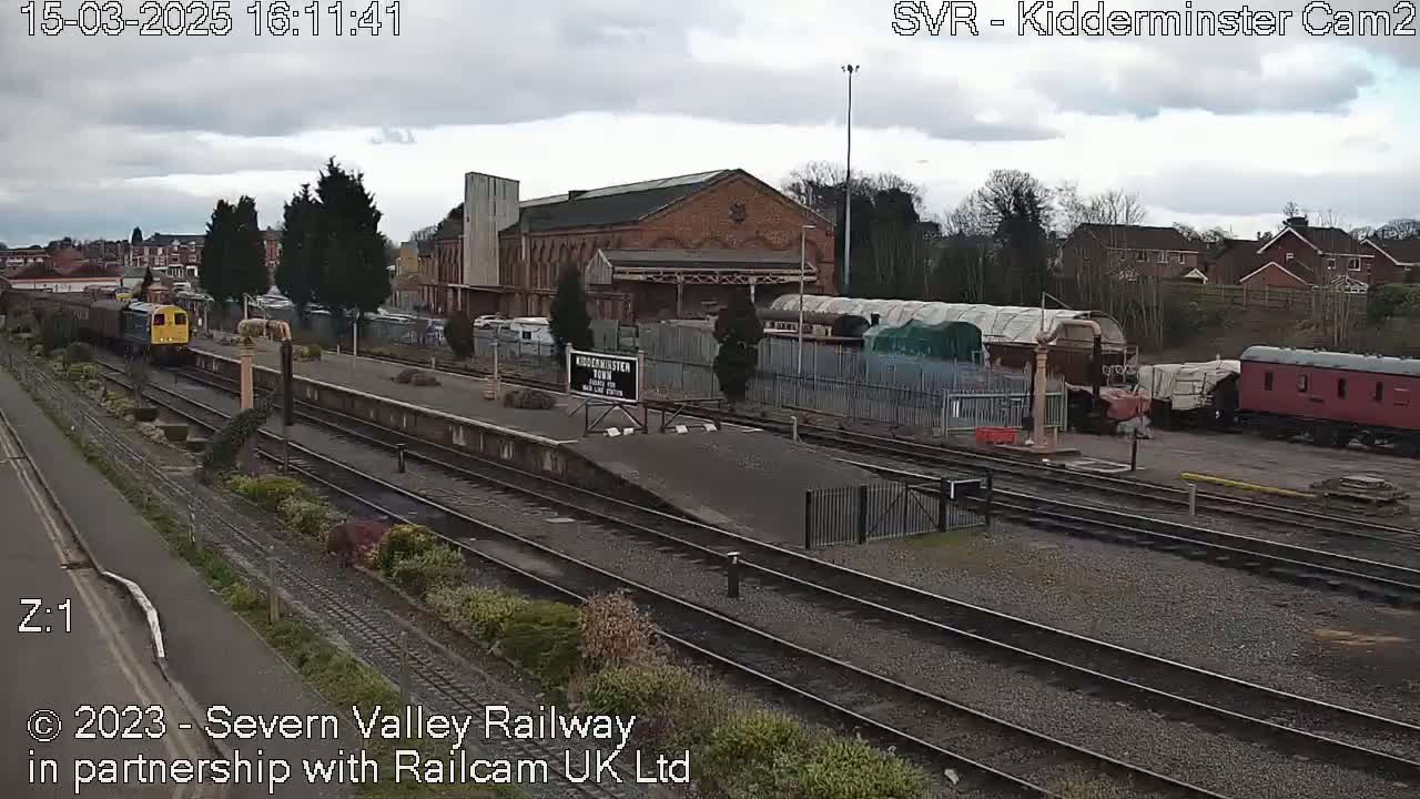 A train is arriving at a railway station on an overcast day.