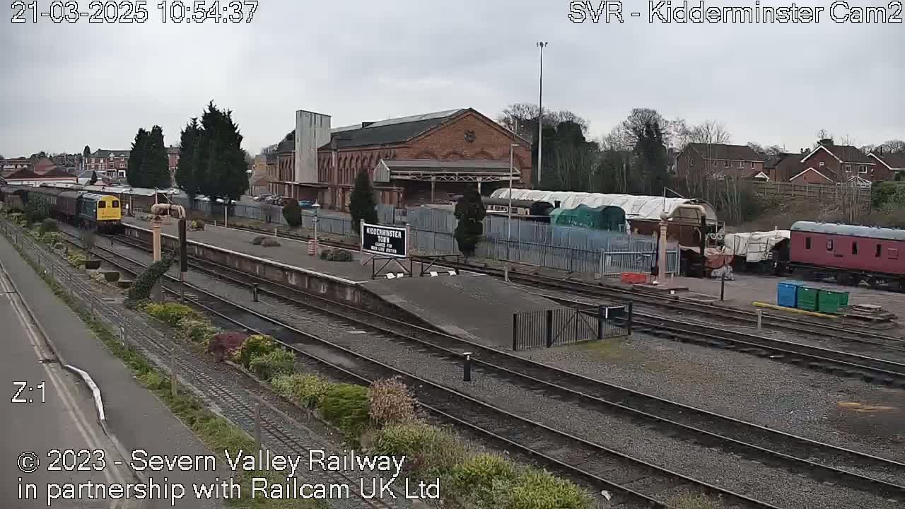 A train is arriving at a railway station on an overcast day.