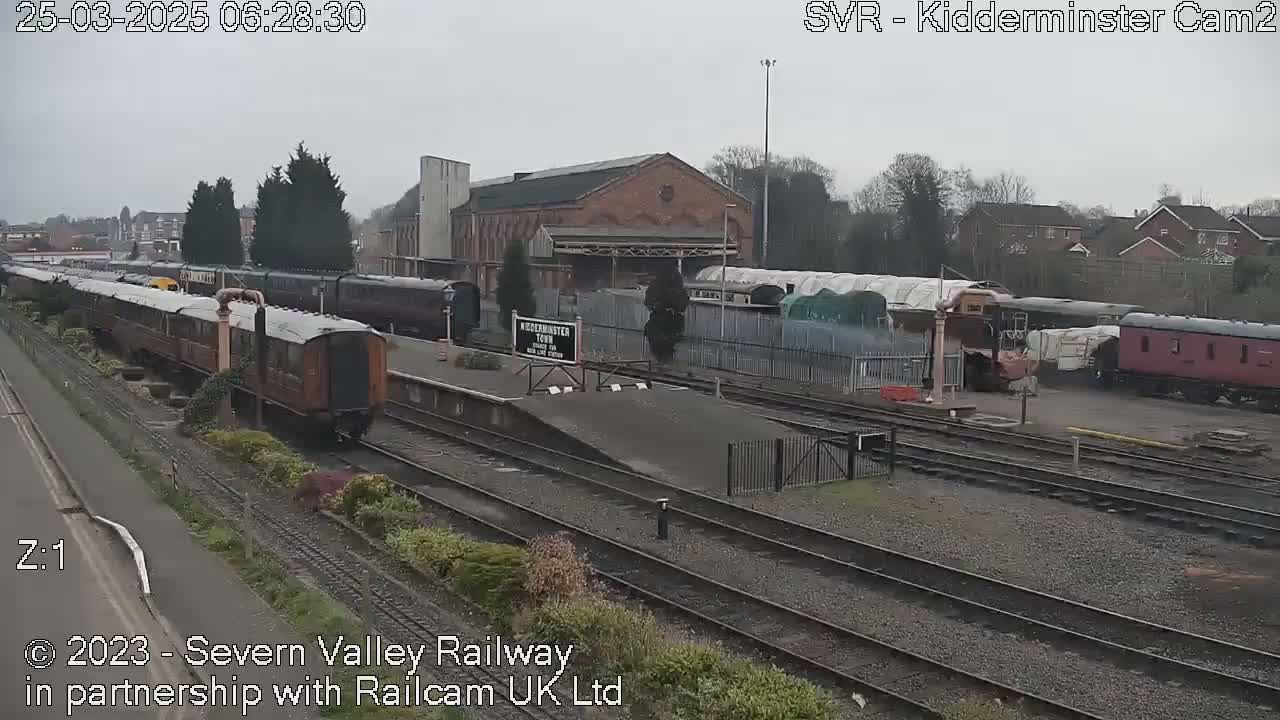 A train station on an overcast day with several passenger cars and locomotives parked on the tracks.