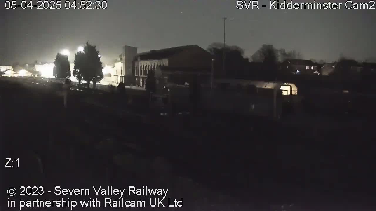 A nighttime, dimly lit view of a building and surrounding area under a dark, overcast sky.