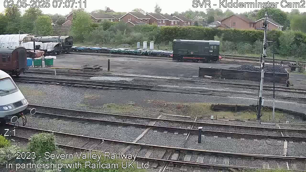 Several trains and railway cars are parked in a rail yard on an overcast day.