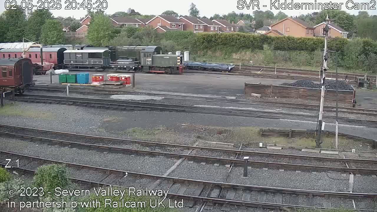 Several railway carriages and locomotives are parked in a yard under an overcast sky.