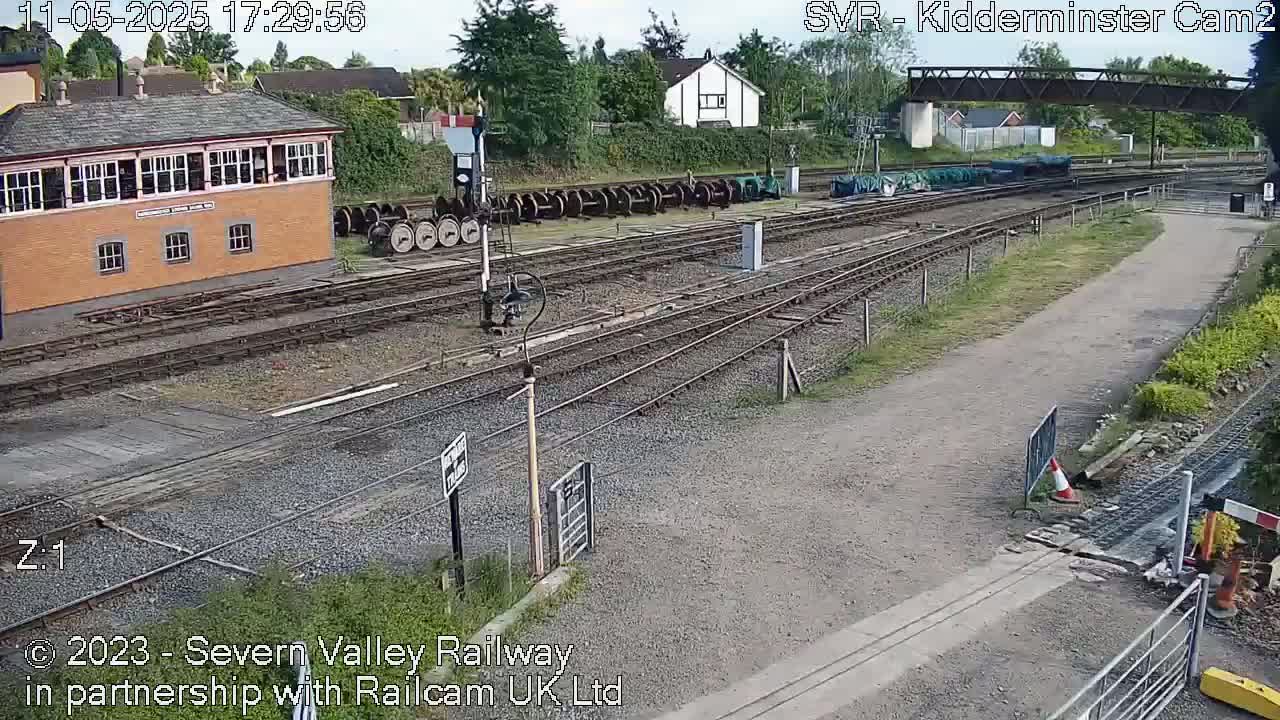 A railway yard with a signal box and several train cars under a partly cloudy sky.