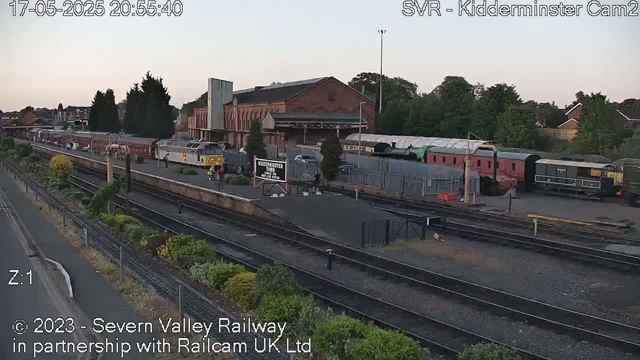 A train station with multiple train cars and locomotives visible at dusk.