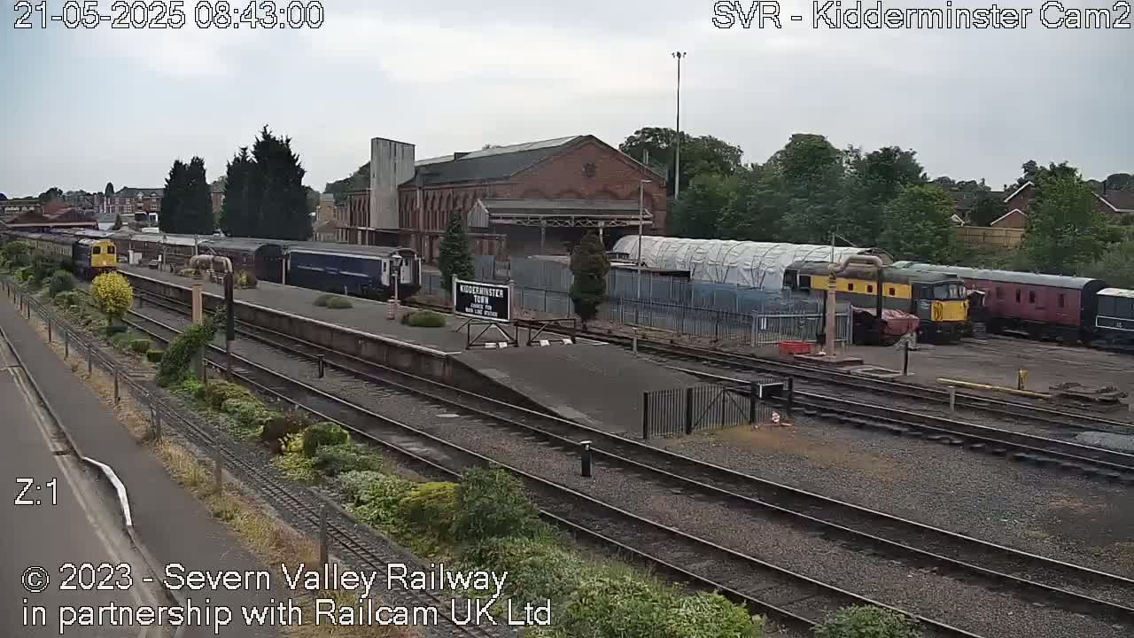 A train station with several trains on the tracks under an overcast sky.