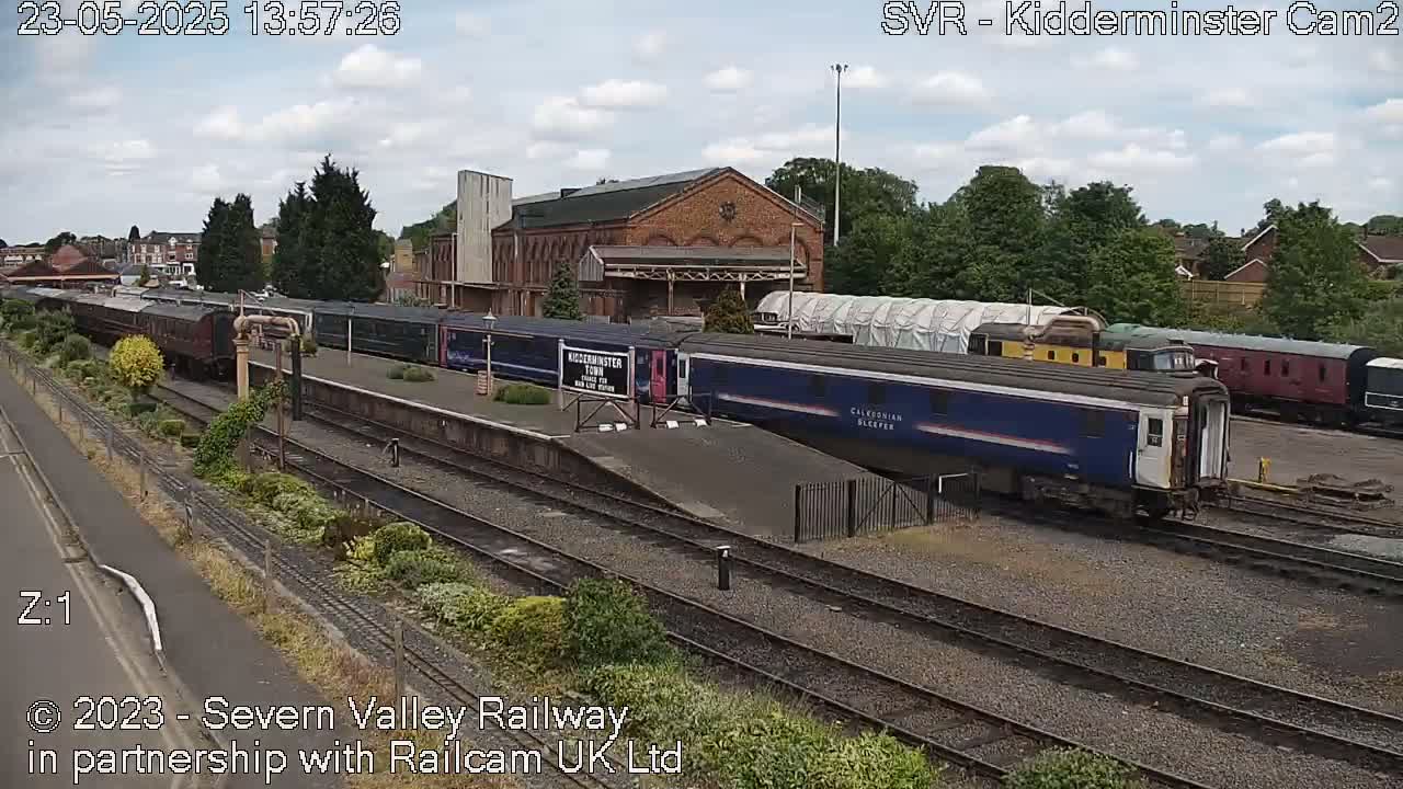 Several passenger trains are at a railway station on a partly cloudy day.