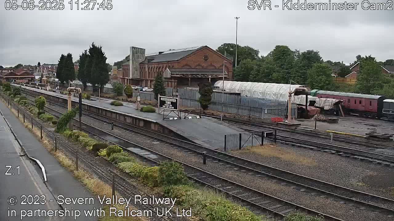 A train station with several train cars and a brick building is seen on an overcast day.