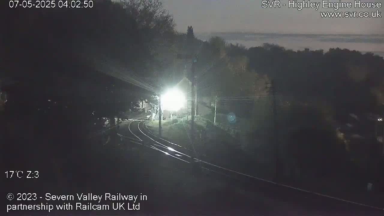 A nighttime view of a dimly lit train yard with a low fog or mist in the background.