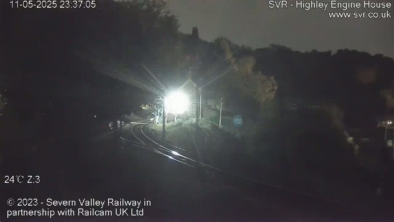 A brightly lit train station at night, with train tracks leading into the darkness.
