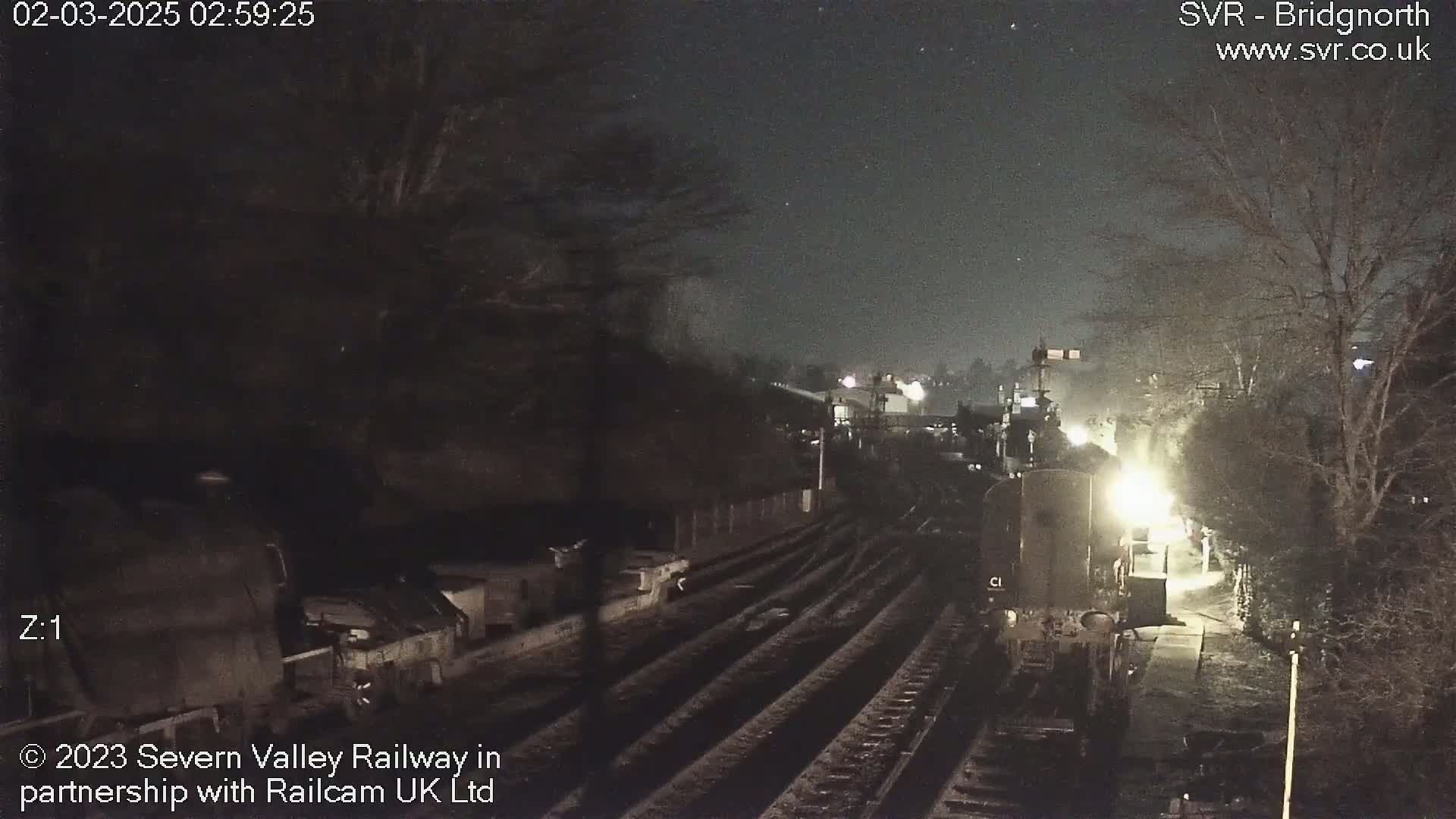 A nighttime view of a train at a railway station under a clear, dark sky.
