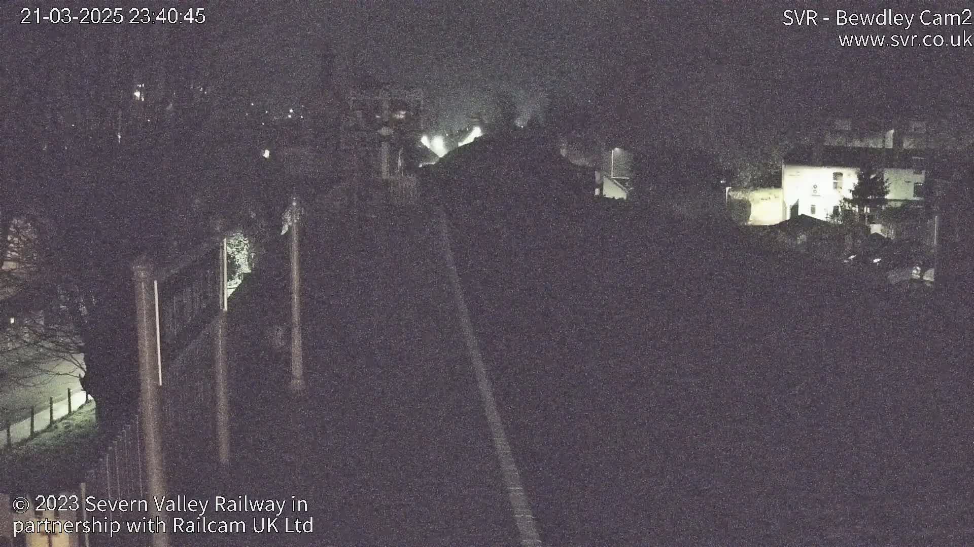 A nighttime, low-light view of a railway line and surrounding buildings.