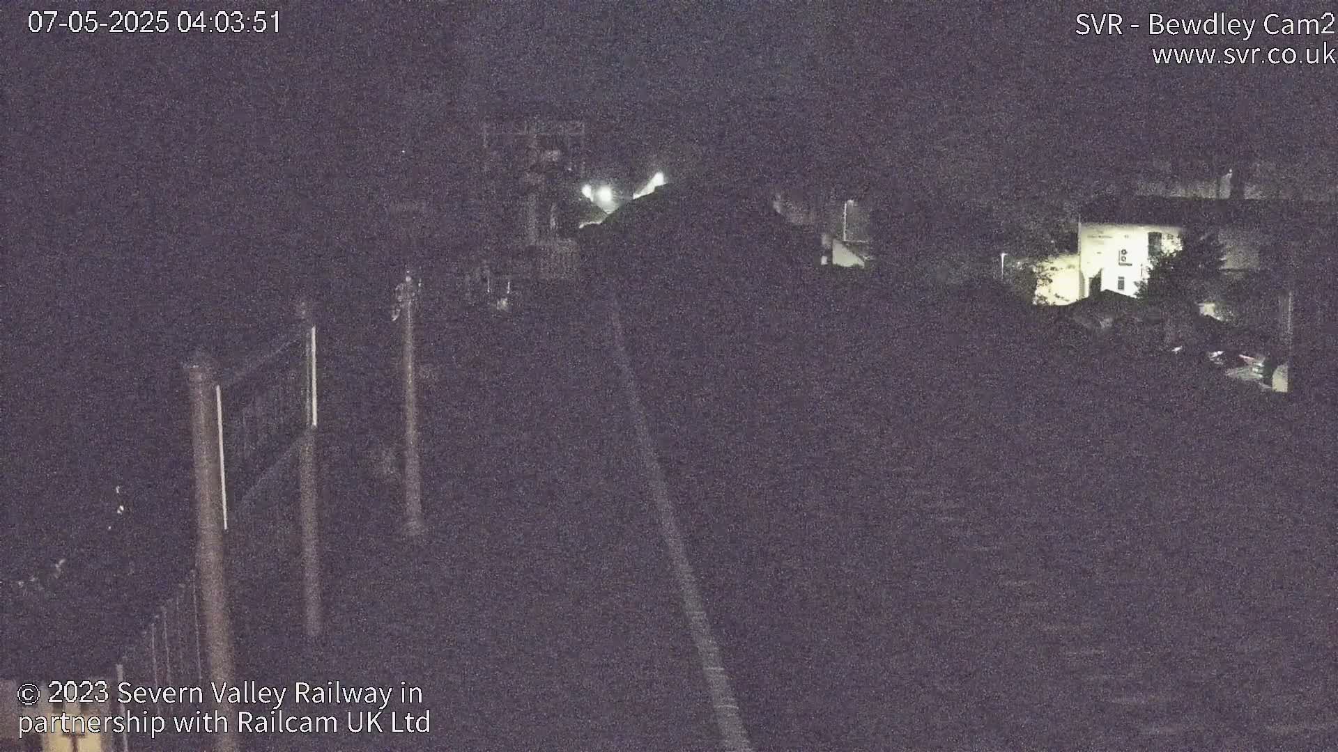A nighttime, low-light view of a railway line and surrounding buildings.