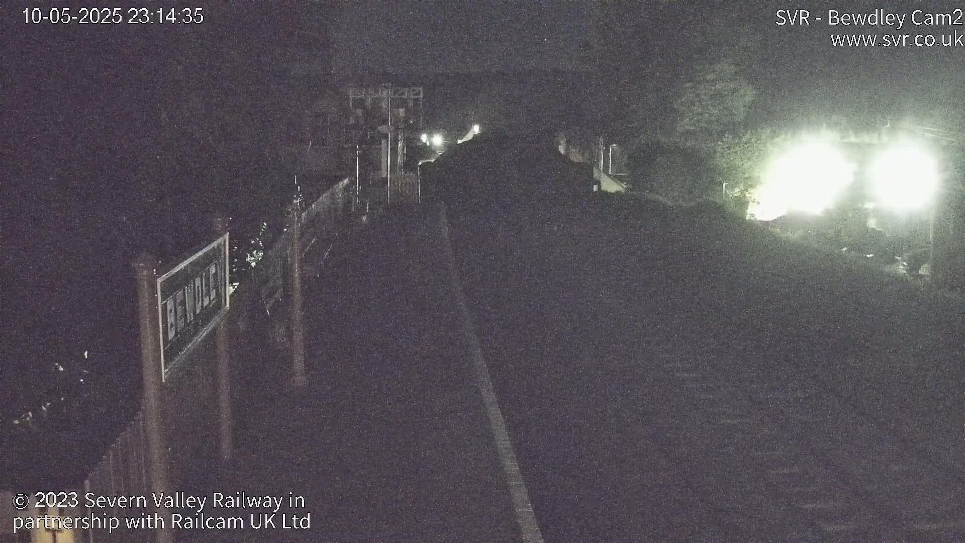 A nighttime, dimly lit view of a train approaching a station.