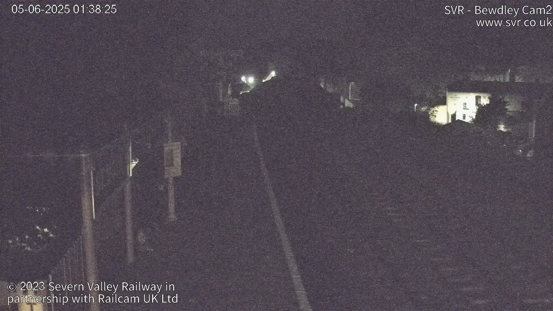 A nighttime, low-light view of a railway track and surrounding buildings.