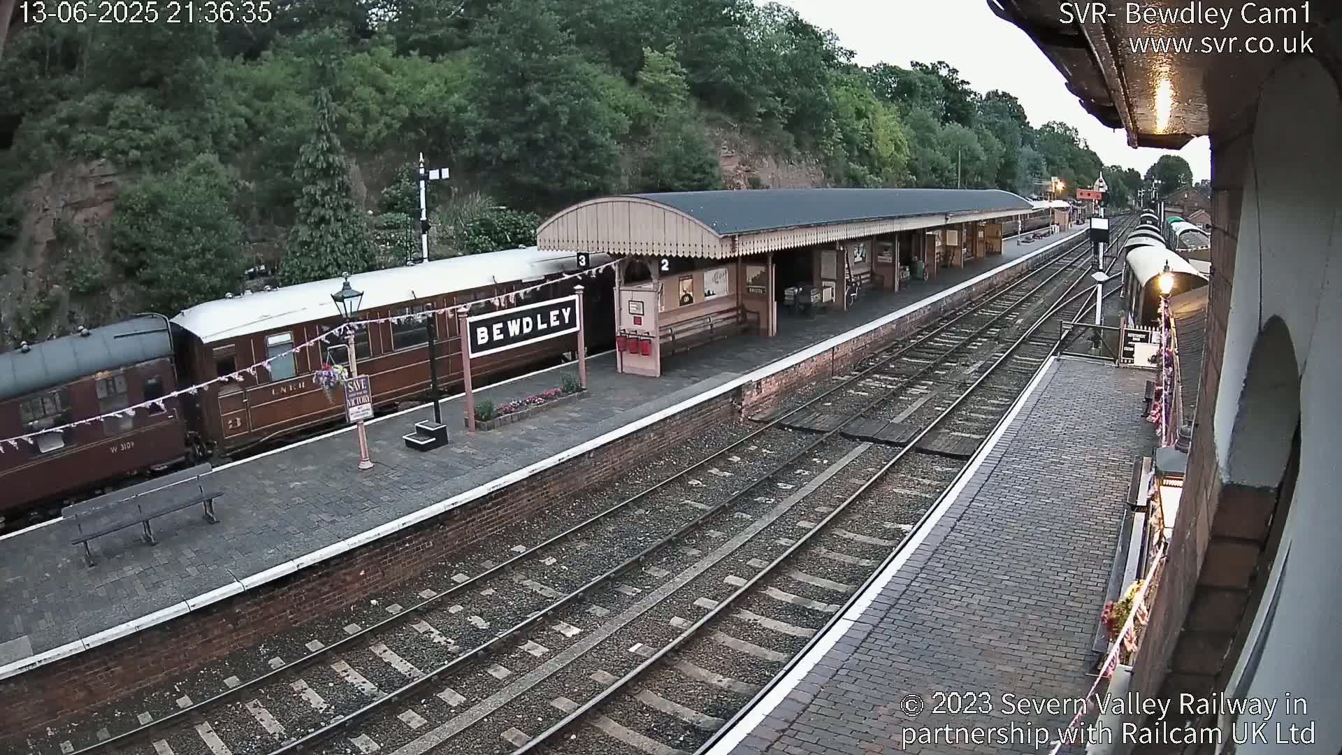 A train is parked at a station platform under an overcast sky.