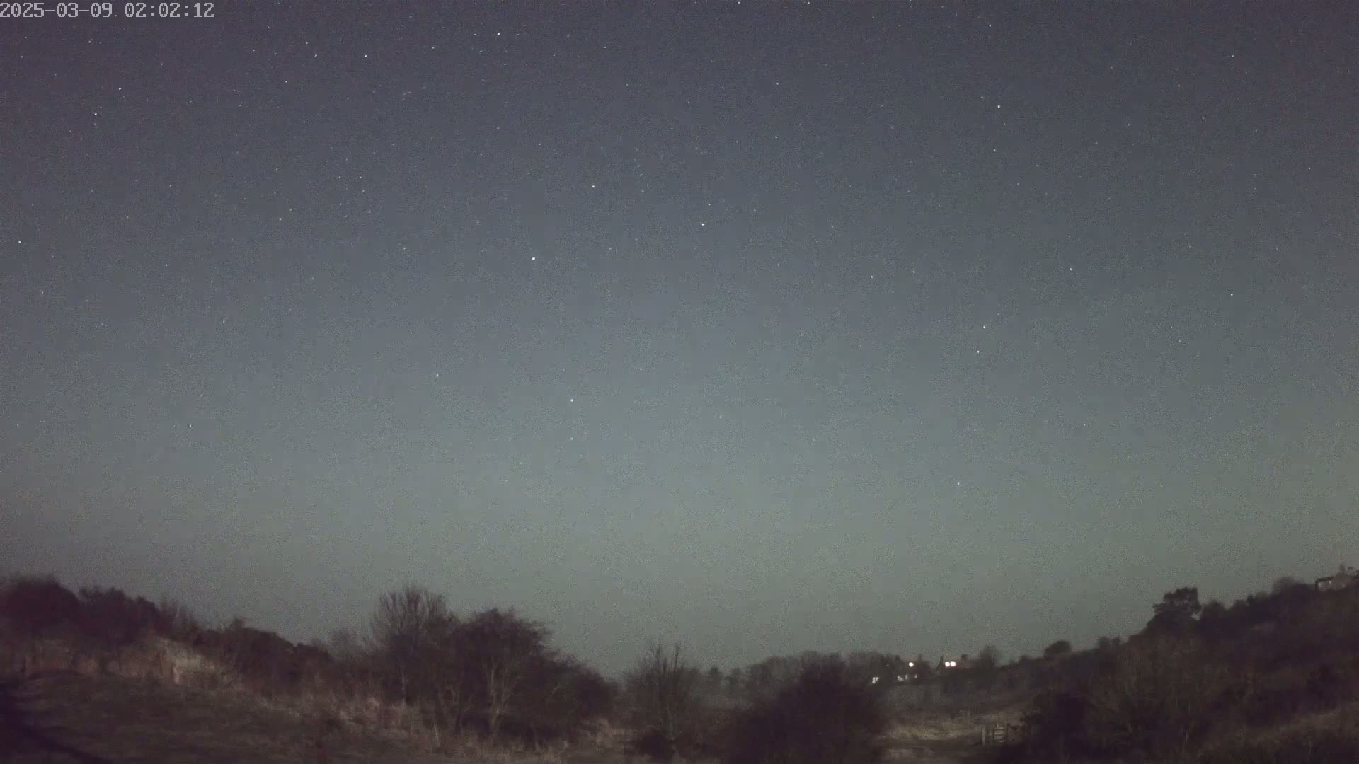 A night scene shows a star-filled sky over a dark, treeline landscape.