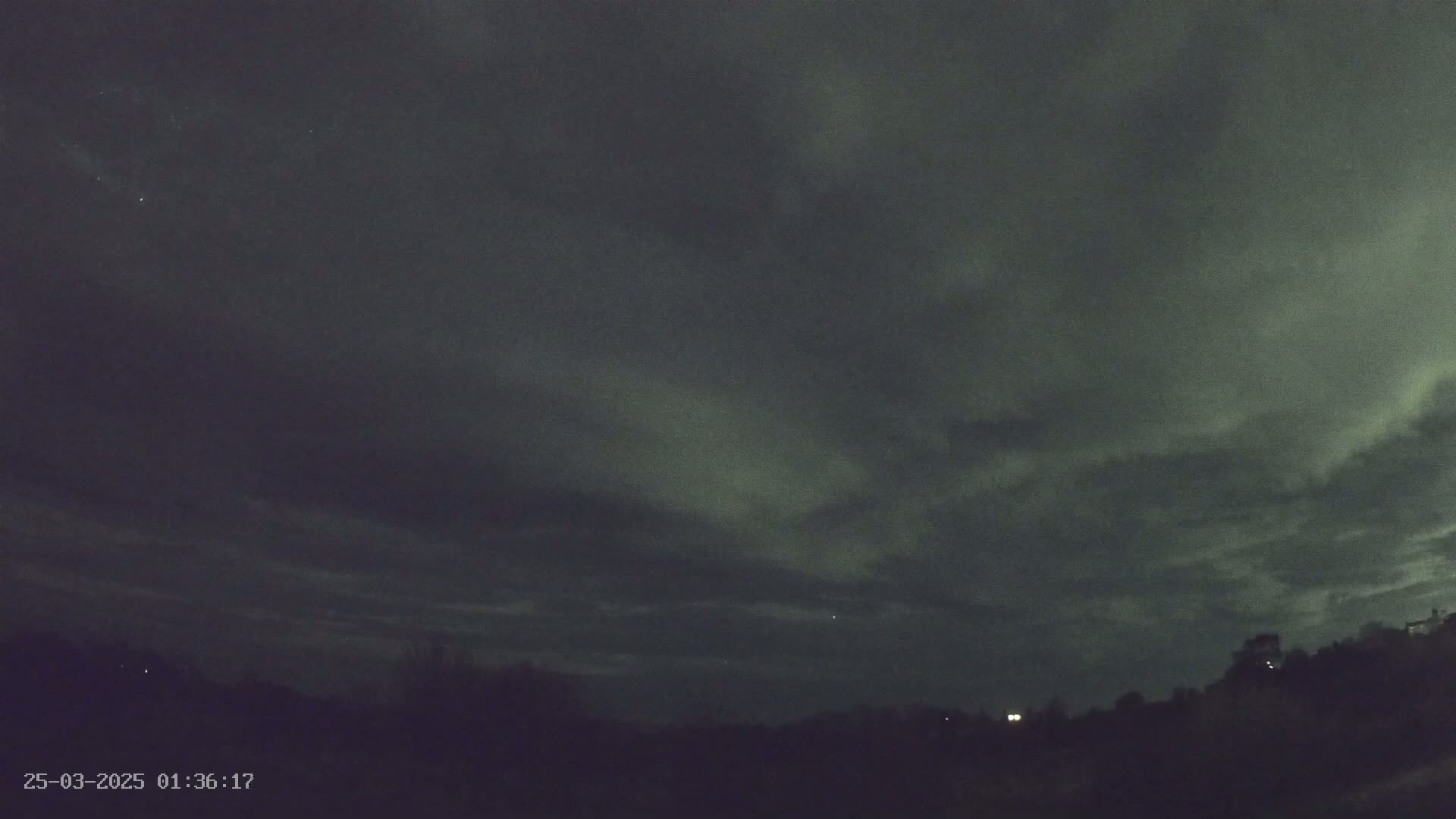 A faint, greenish aurora borealis is visible in the night sky above a dark, silhouetted landscape.