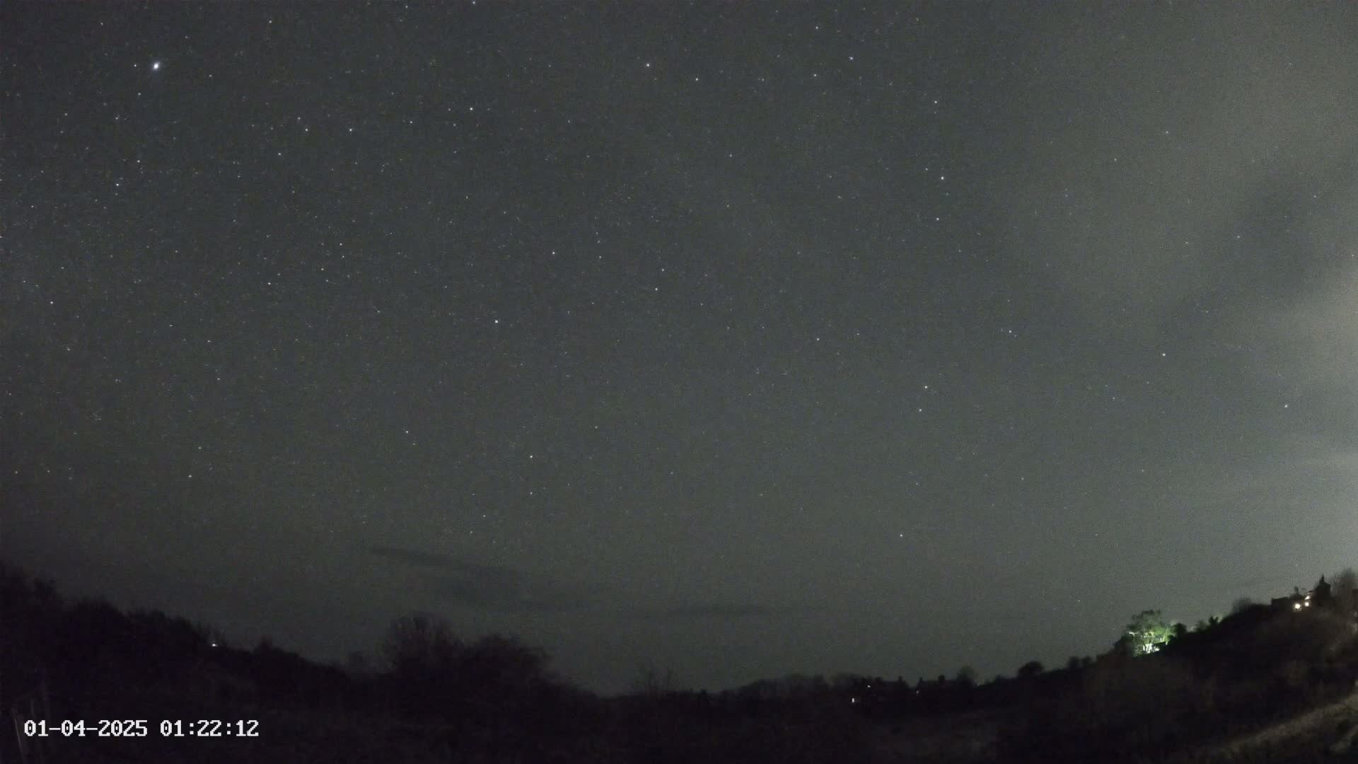 A night sky filled with stars is visible above a dark, silhouetted landscape with some distant lights.