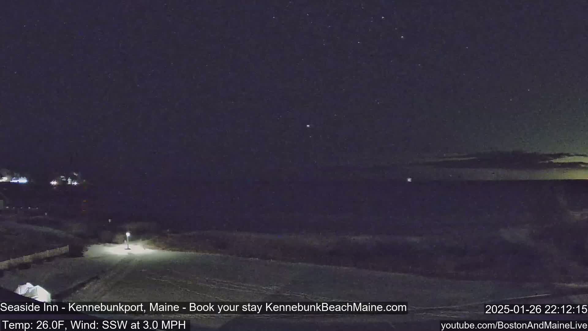 A nighttime view of a snow-covered shoreline under a clear, starry sky with a gentle south-southwesterly wind.