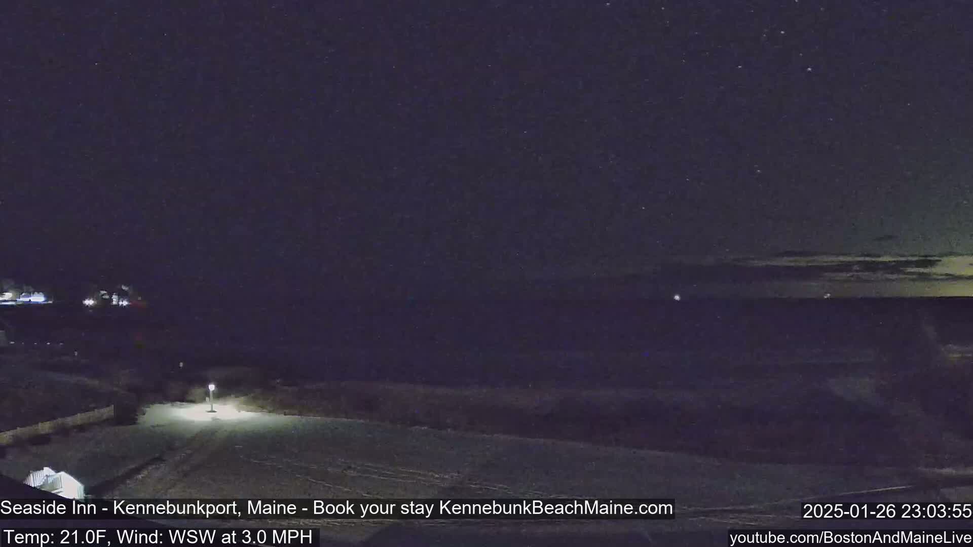 A nighttime view of a snow-covered area near a dark ocean under a starry sky.