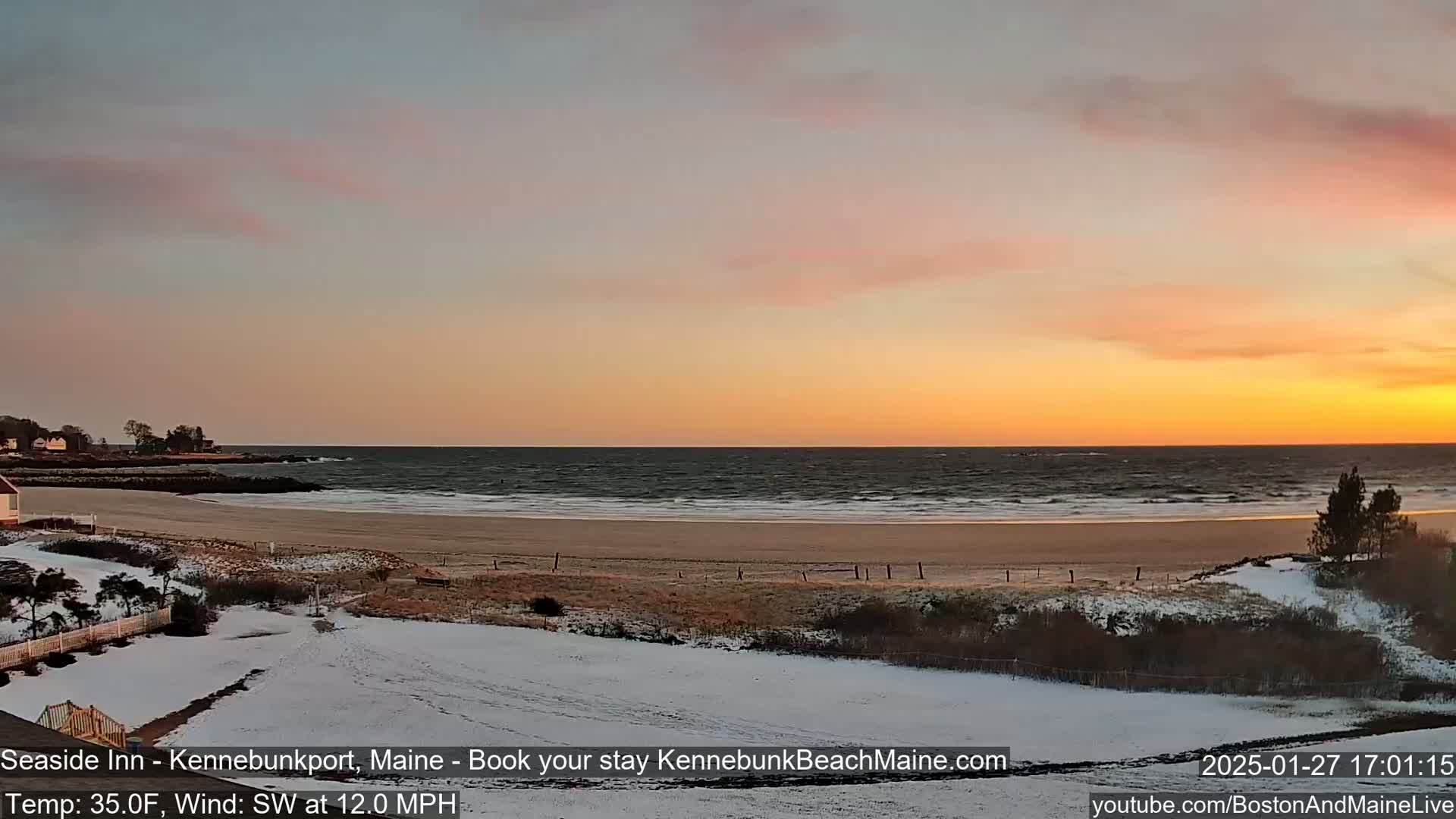 A snow-covered beach scene at sunset, with a calm ocean and a light southwest wind.
