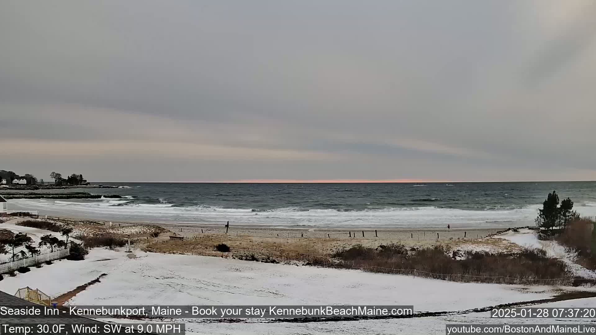 A snow-covered beach with a choppy sea under a gray sky.